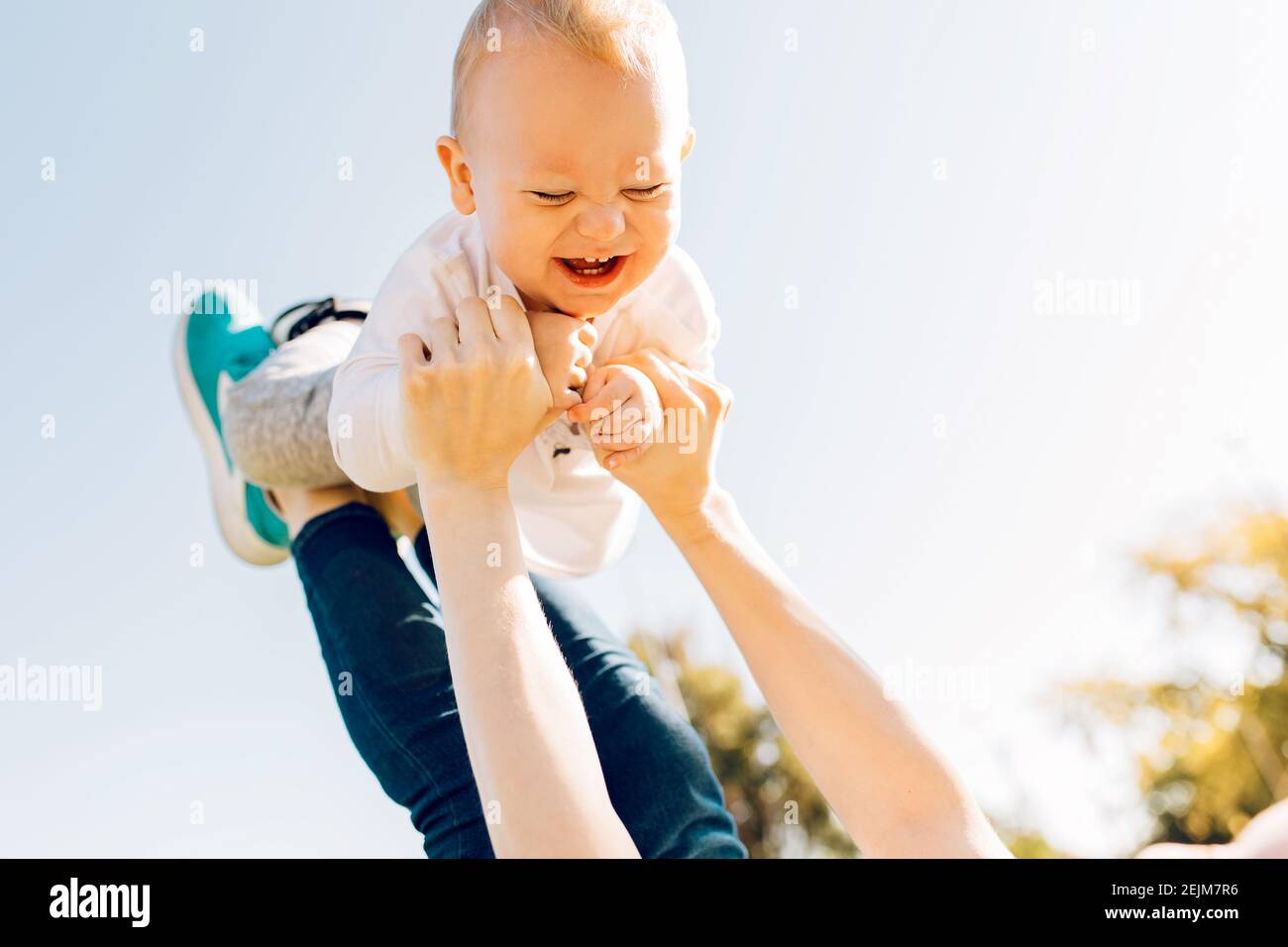 mamma che gioca e lancia un figlio felice mentre ha divertimento insieme nel parco Foto Stock