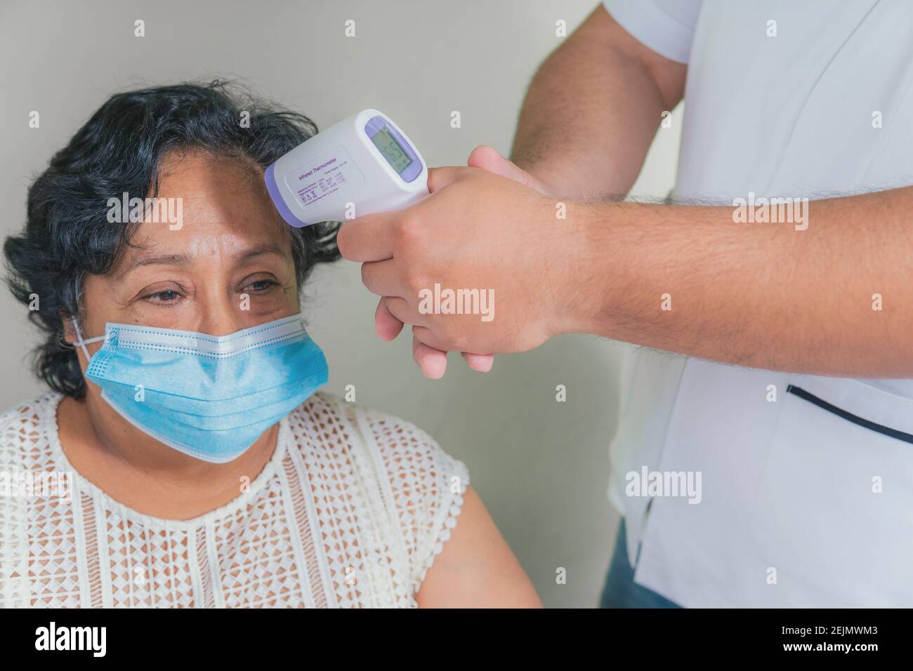 vista di una donna anziana che controlla la temperatura con un termometro digitale Foto Stock