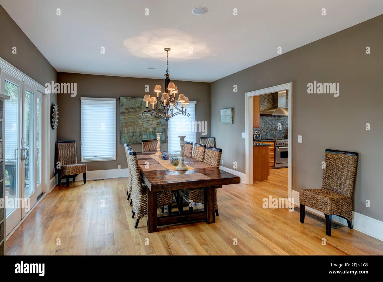 Bella sala da pranzo di lusso con sedie in legno e vimini e pavimenti e tavolo in legno duro. Foto Stock