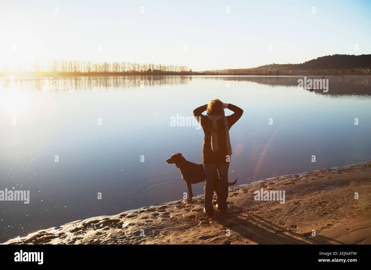 Donna e il suo cane che camminano sul fiume. Foto Stock