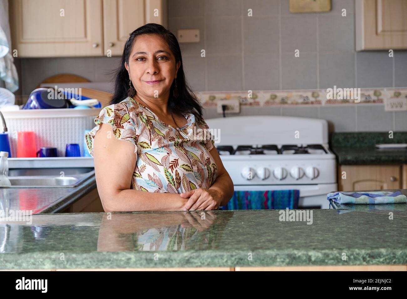 Orgogliosa donna ispanica in posa in cucina pulita-sorridente mamma in piedi in cucina-donna in cucina non cucinare Foto Stock