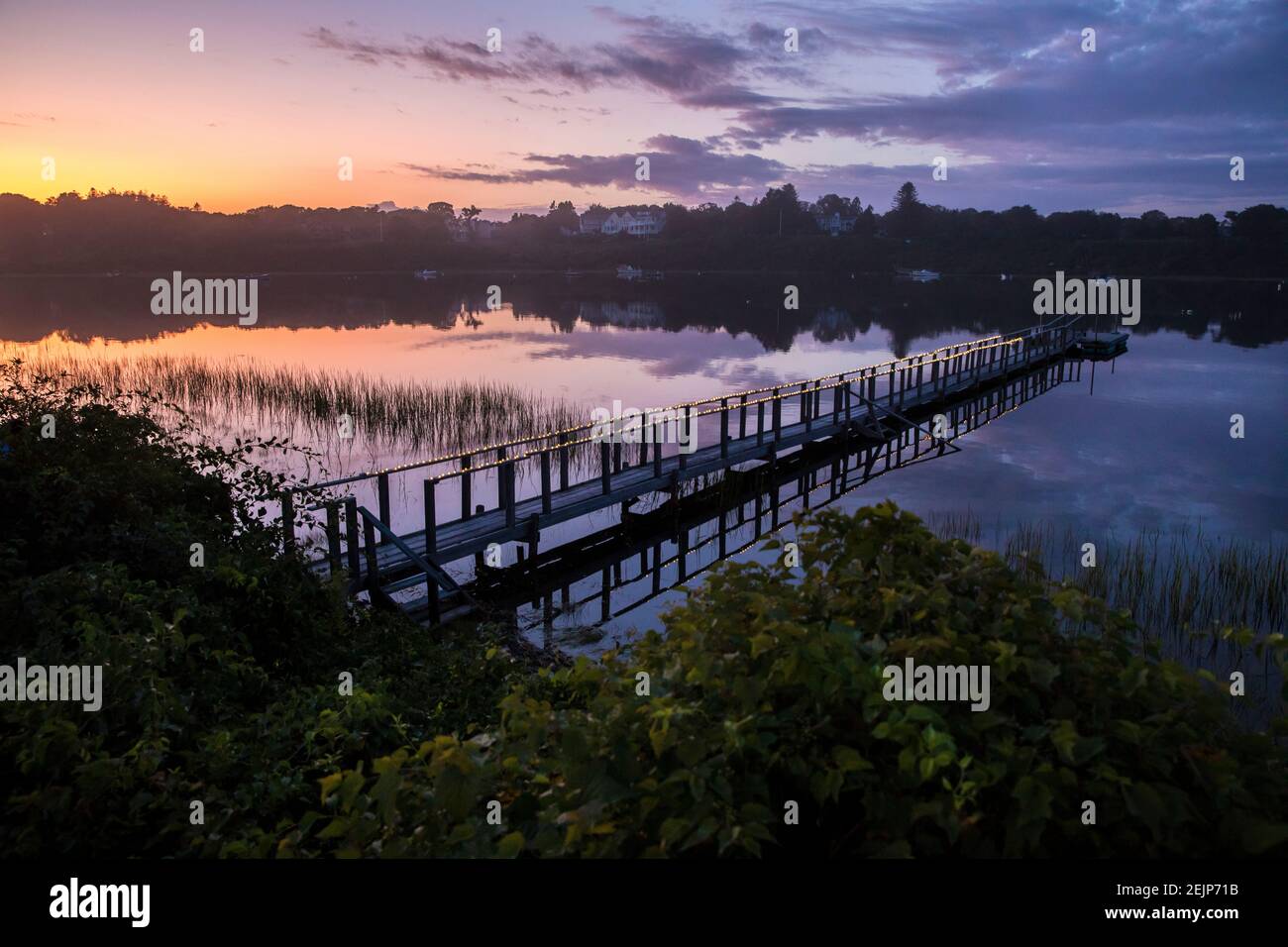 Lungo molo con luci su Little Mill Pond al tramonto con cielo viola Foto Stock