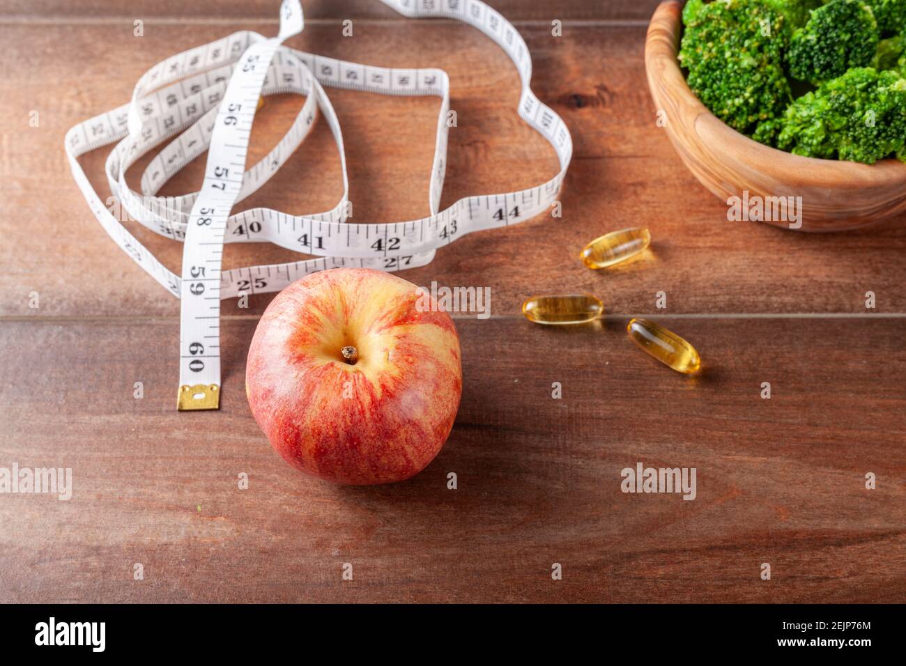 Una forma fisica, ottenere in forma, dieta, vita sana idea immagine con una vista ravvicinata in alto di un nastro di misurazione, integratori alimentari pillole, fresco broccoli Foto Stock
