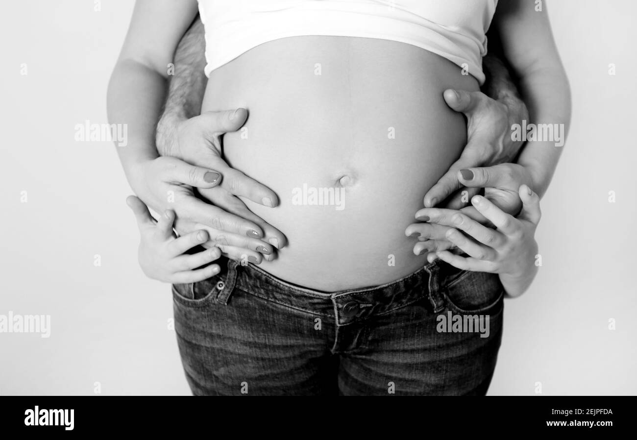 Le mani di famiglia felice insieme toccano la pancia della madre incinta Foto Stock