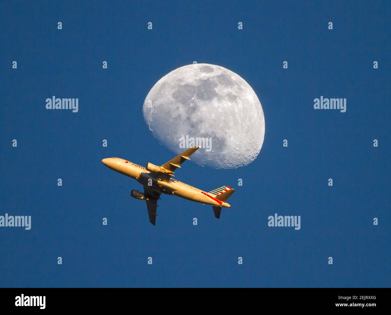 Un jet passeggeri American Airlines passa vicino a una luna gibbosa in ceretta poco dopo il decollo. Foto Stock
