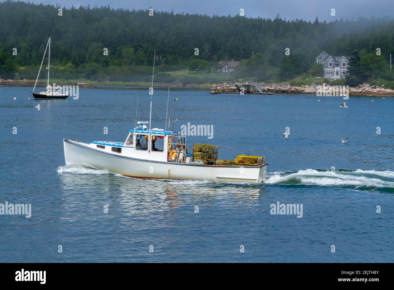 Una barca di aragosta con le trappole che si dirigono verso l'esterno per controllare le sue trappole. Foto Stock
