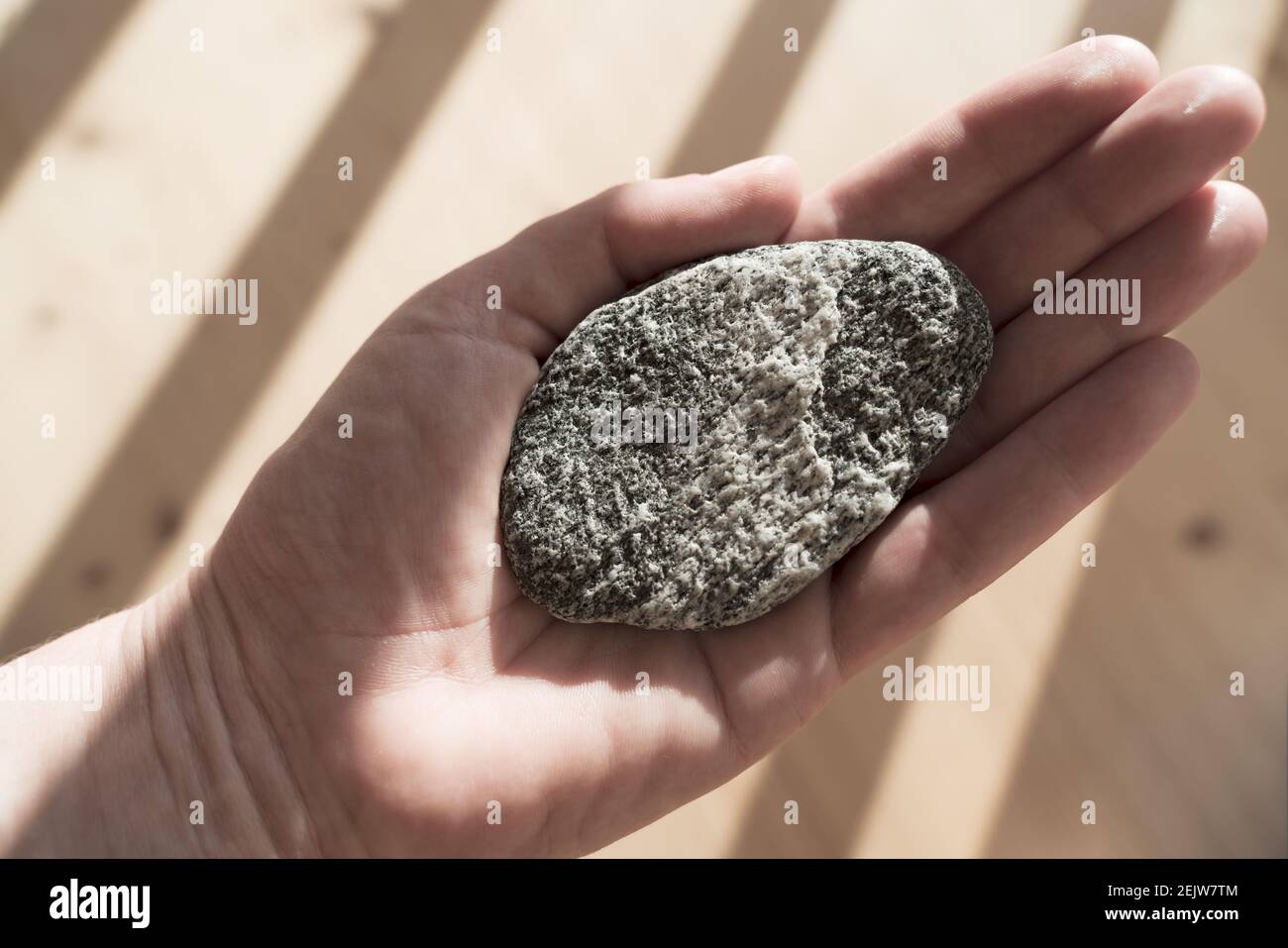 Donna che tiene la pietra rotonda di forma illuminata dai raggi del sole come un simbolo di equilibrio per la meditazione Foto Stock