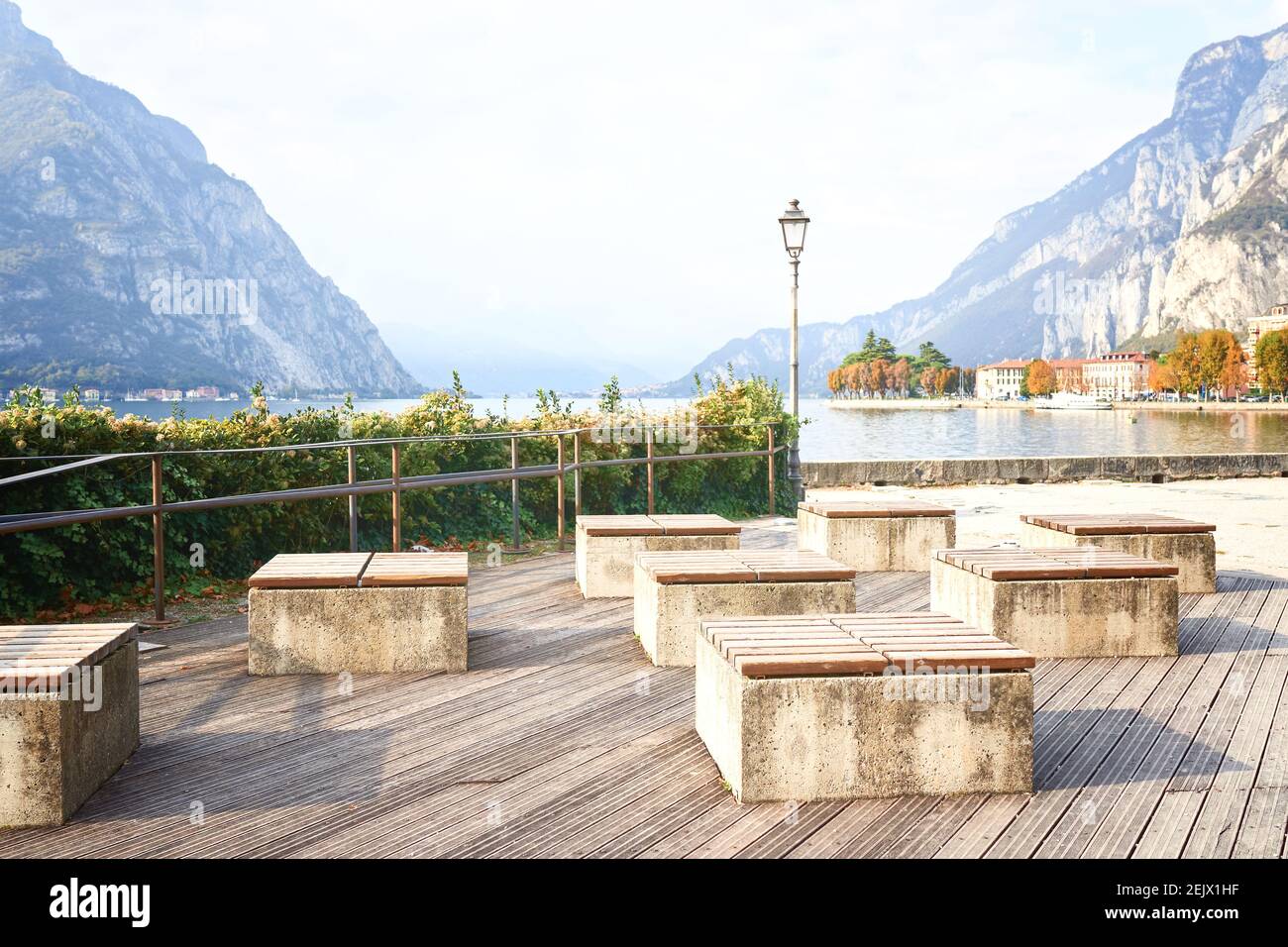 Moderne panchine in terrapieno in una giornata di sole vicino al lago di Como. Panca esterna in legno naturale in stile giardino zen. Miglioramento della città, urbano Foto Stock