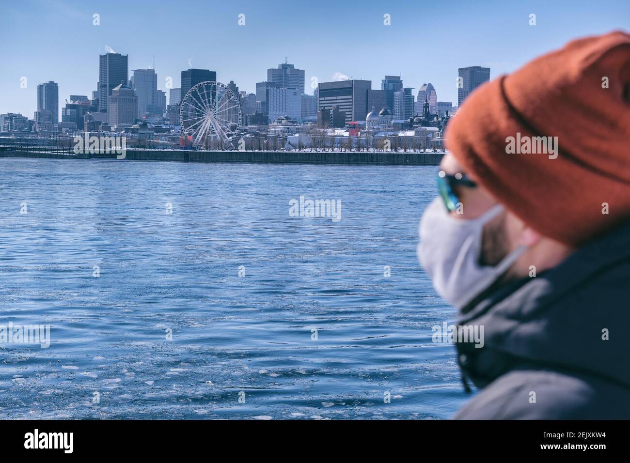 Giovane uomo che indossa una maschera protettiva per la protezione Coronavirus guardando Skyline di Montreal Foto Stock