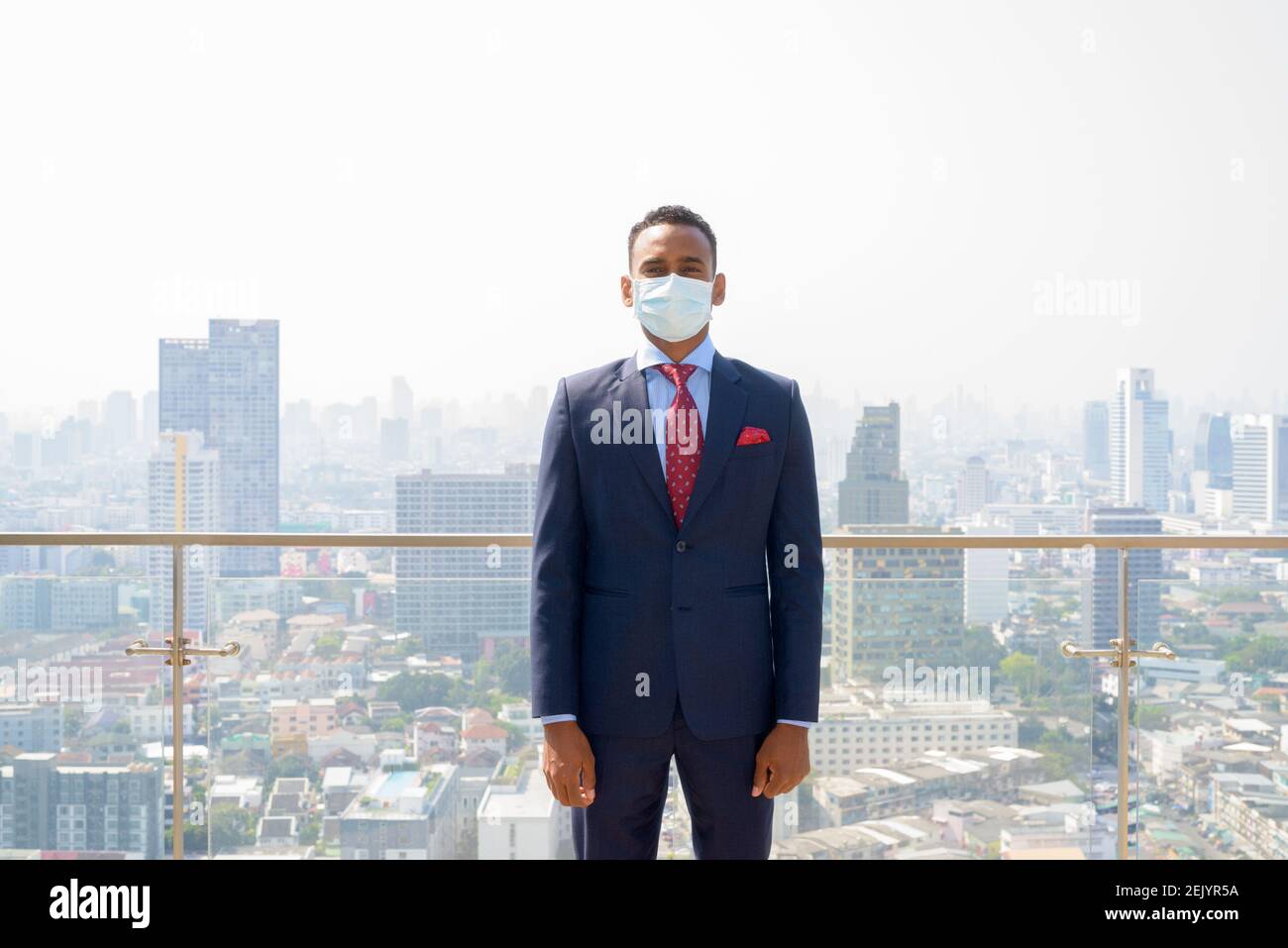 Uomo d'affari africano con maschera medica chirurgica per la protezione contro la città visualizza Foto Stock
