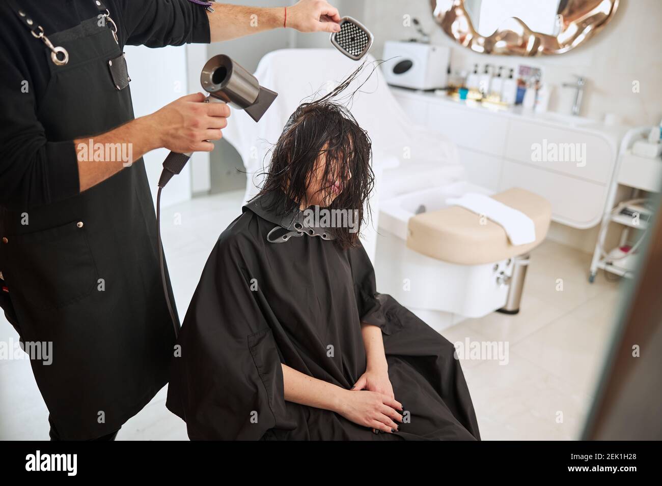 Professionista del salone che utilizza una spazzola a pale e un'asciugatrice Foto Stock