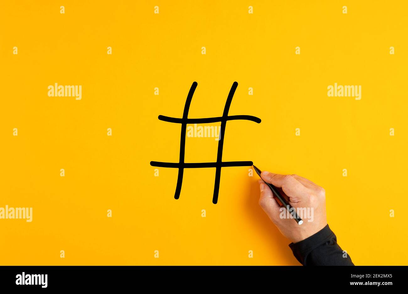 Mano maschile che disegna un simbolo hashtag o un'icona su sfondo giallo. Foto Stock