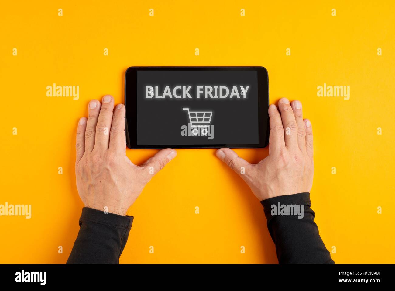 Mano maschile tenendo un tablet digitale che visualizza la parola Black Friday con un'icona del carrello sullo schermo. Vendita Black Friday e shopping mania conc Foto Stock