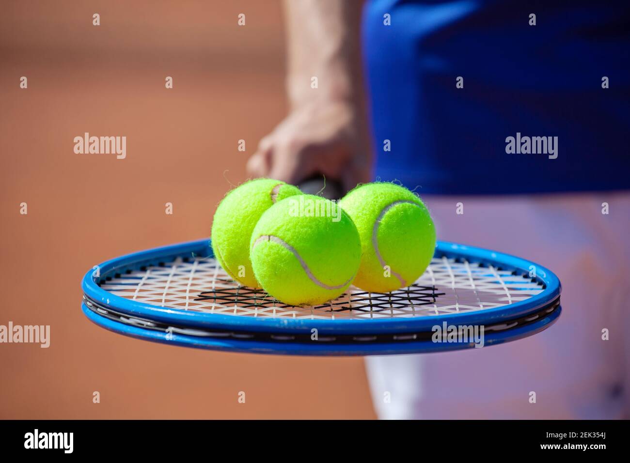 Giocatore di tennis che tiene una racchetta da tennis con tre palle sopra esso Foto Stock