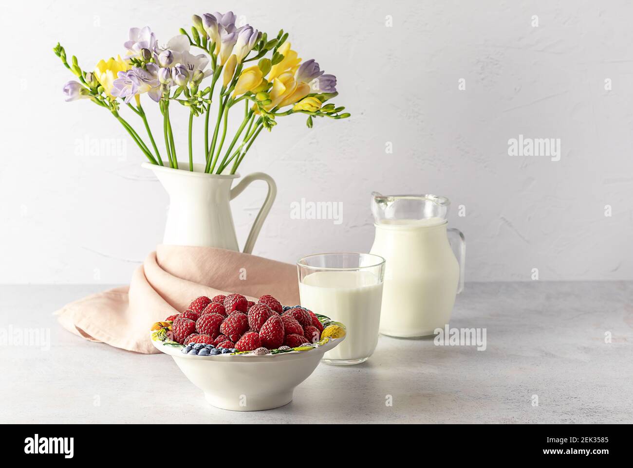 Spuntino estivo sano - lampone e latte, con fiori freschi Foto Stock