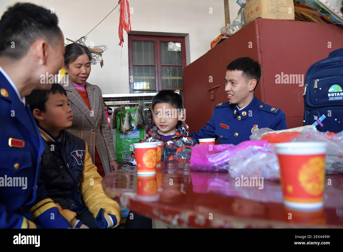 (210223) -- NANCHANG, 23 febbraio 2021 (Xinhua) -- Zhang Jiagang (1° R) e il suo collega visitano i bambini che aiutano nella Contea di Fenyi, città di Xinyu, nella provincia di Jiangxi della Cina orientale, 20 febbraio 2021. Zhang Jiagang, 24 anni, ora vigile del fuoco nella Contea di Fenyi della città di Xinyu, è stato trovato abbandonato e adottato 24 anni fa da Tang Caiying, che ora ha 85 anni. Tang Caiying e suo marito hanno allevato la propria figlia e sei fondazioni da soli per stipendi, vendendo verdura e rifiuti. Nel 2001, i vigili del fuoco nella contea di Fenyi iniziarono ad aiutare Tang Caiying e la sua famiglia dopo aver conosciuto thei Foto Stock