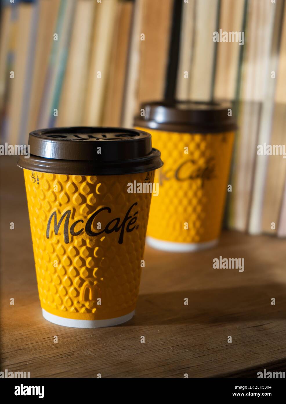 Ucraina, Kiev - 17 febbraio 2021: Bicchiere giallo di caffè da McDonald's. Bicchiere di carta McCafe. Tazza di caffè offee sul tavolo con ombre. Menu in fast food Foto Stock