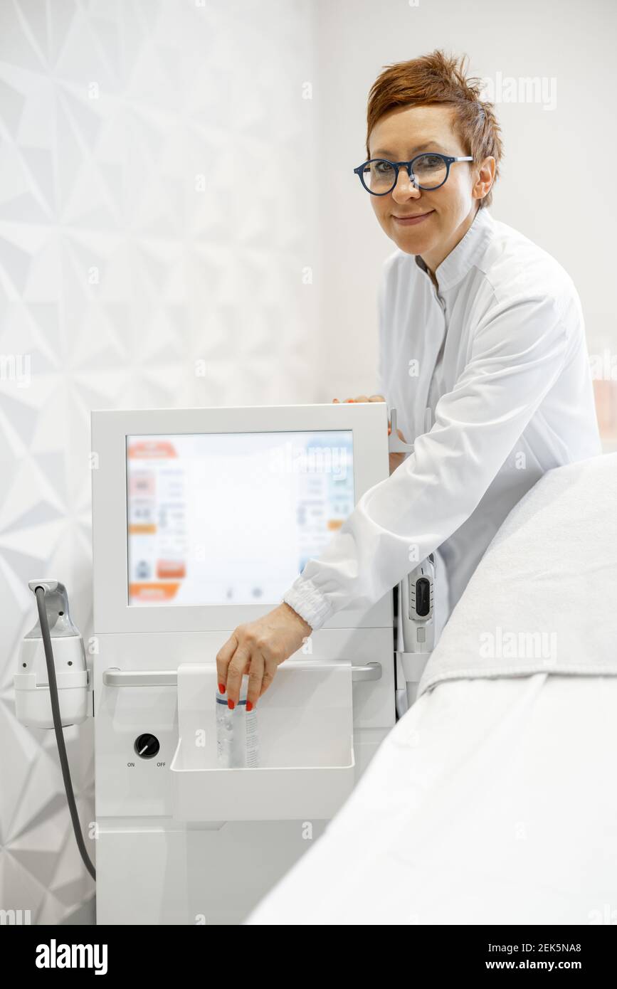 Cosmetologo con dispositivo di sollevamento a ultrasuoni in clinica di bellezza Foto Stock