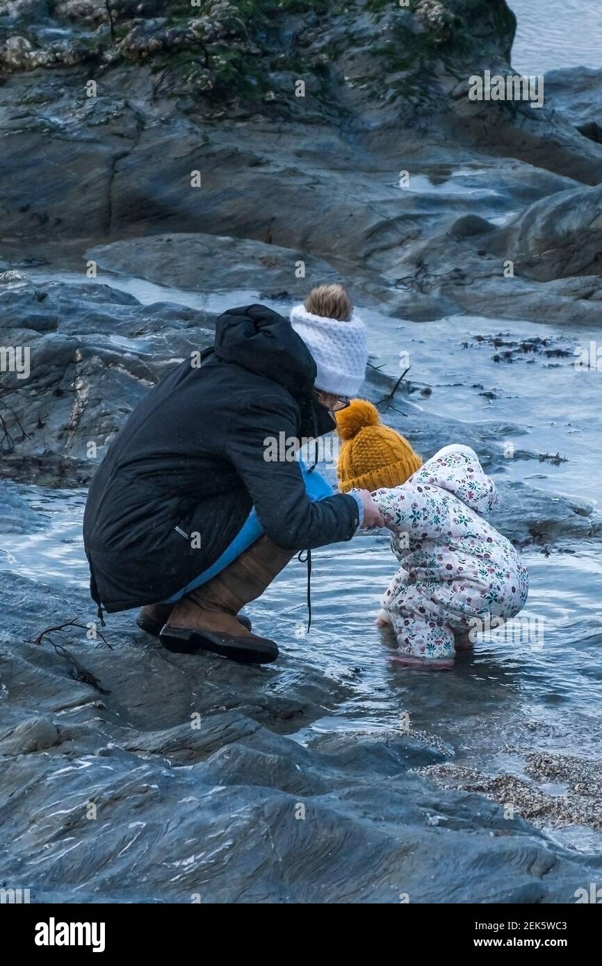 Una madre e il suo bambino esplorano le piscine rocciose di Little Fistral in Cornovaglia. Foto Stock