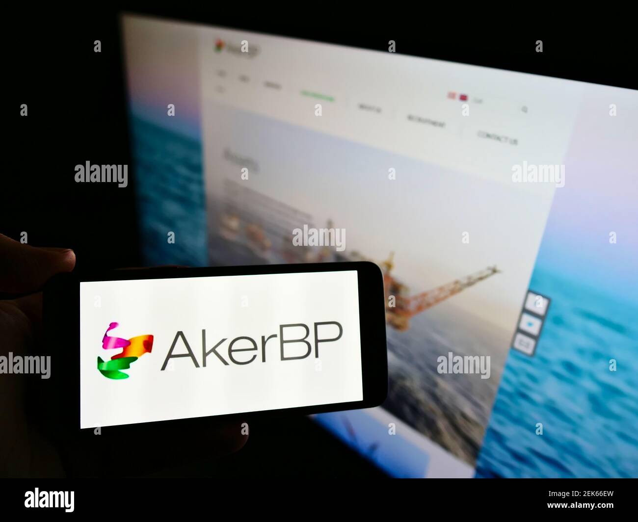 Persona che detiene il cellulare con il logo aziendale della società norvegese di petrolio e gas Aker BP ASA sullo schermo davanti alla pagina web. Mettere a fuoco il display del telefono. Foto Stock