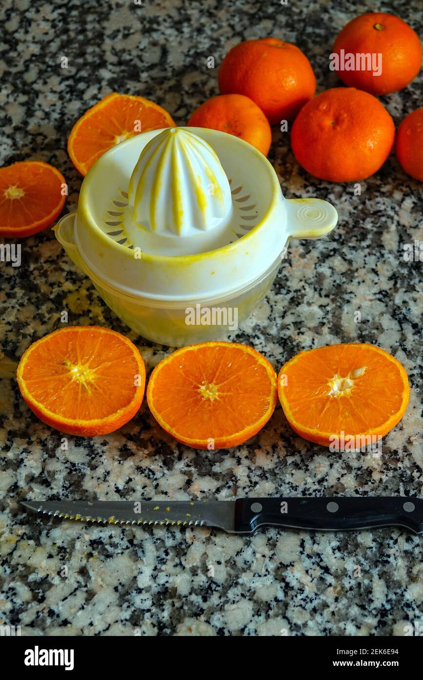 Arance fresche pronte per la spremitura per preparare il succo d'arancia sulla superficie di lavoro della cucina in granito. Foto Stock