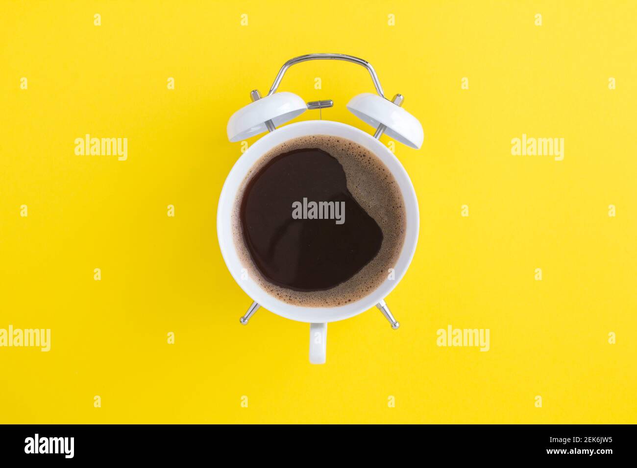 Caffè nero sul quadrante della sveglia bianca al centro dello sfondo giallo Foto Stock