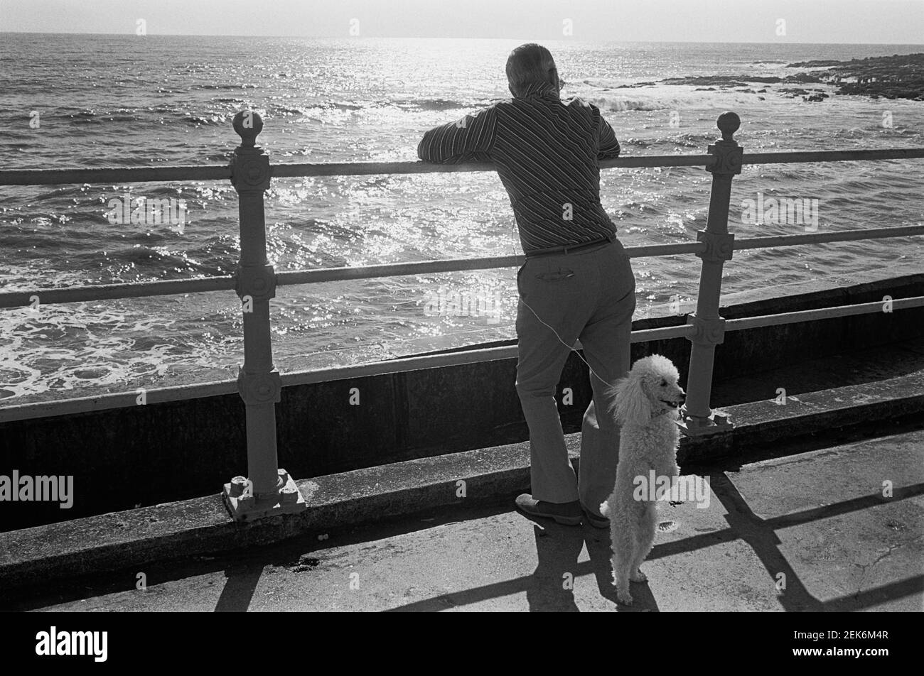 Un uomo e il suo cane sull'Esplanade a Porthcawl, Galles del Sud, 1977 Foto Stock