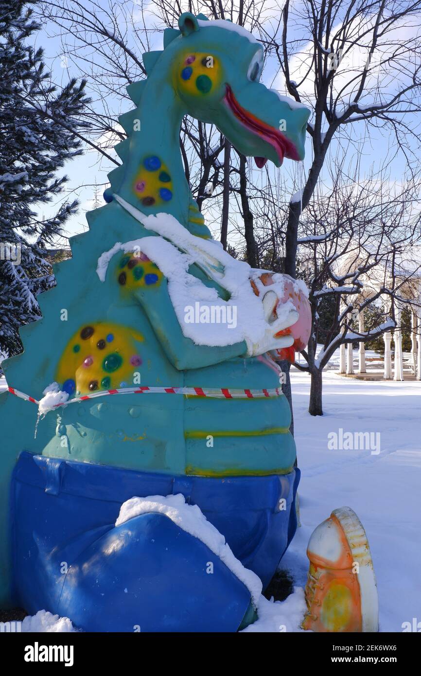 Giocattolo da dinosauro al parco giochi per bambini sotto la neve Foto Stock