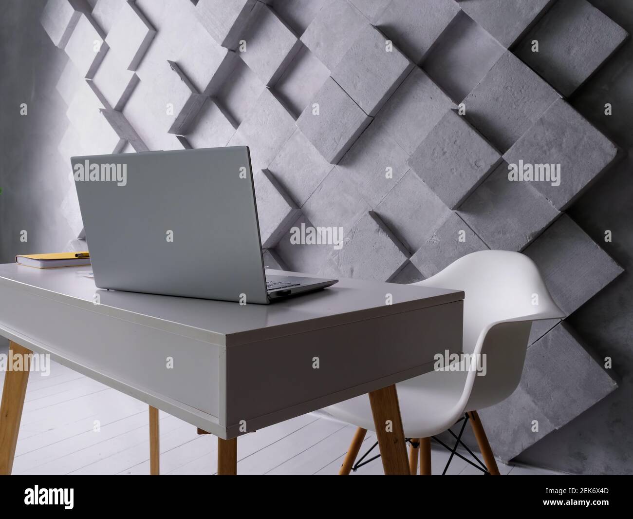 Ambiente di lavoro creativo vuoto. Tavolo con laptop, carte e sedia. Ufficio vuoto. Foto Stock