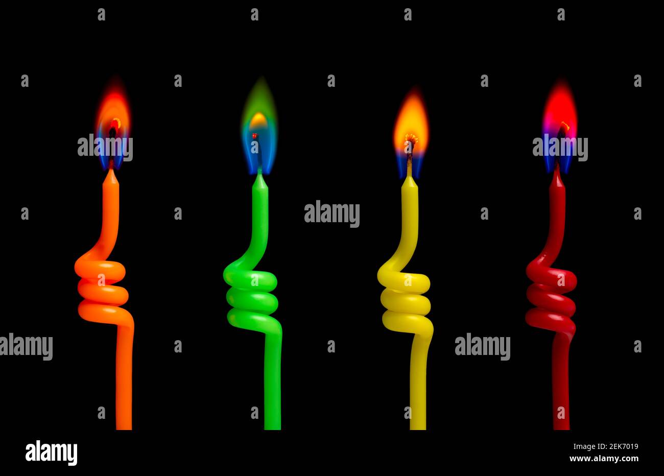 Quattro candele colorate si illuminano sullo sfondo nero Foto Stock