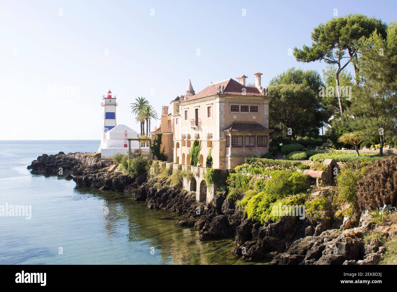 Splendida vista sulla spiaggia, il faro e la villa durante il giorno di sole. Cascais. Portogallo. Foto Stock
