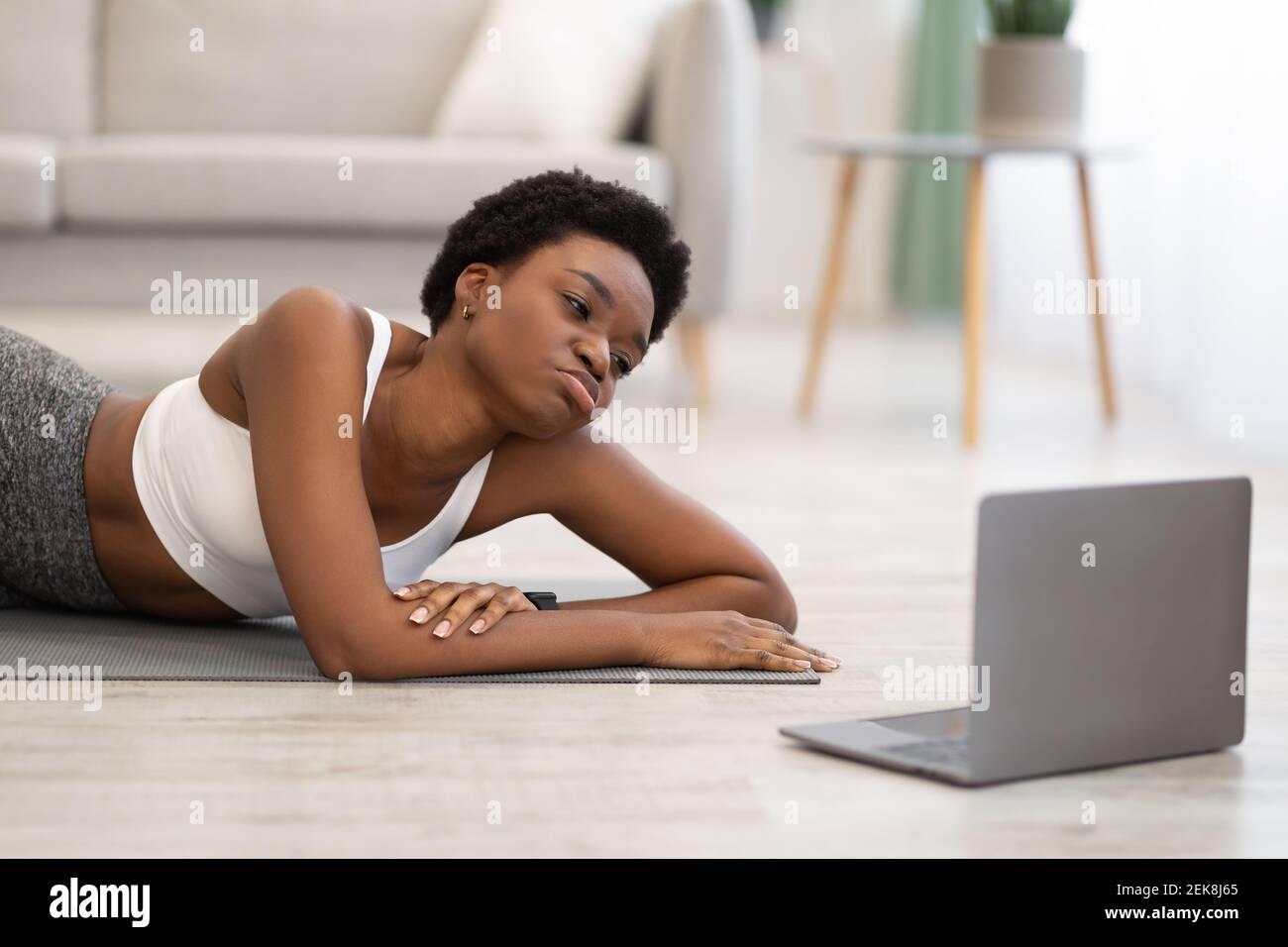 African Woman sdraiato vicino laptop stanco dopo l'allenamento online indoor Foto Stock