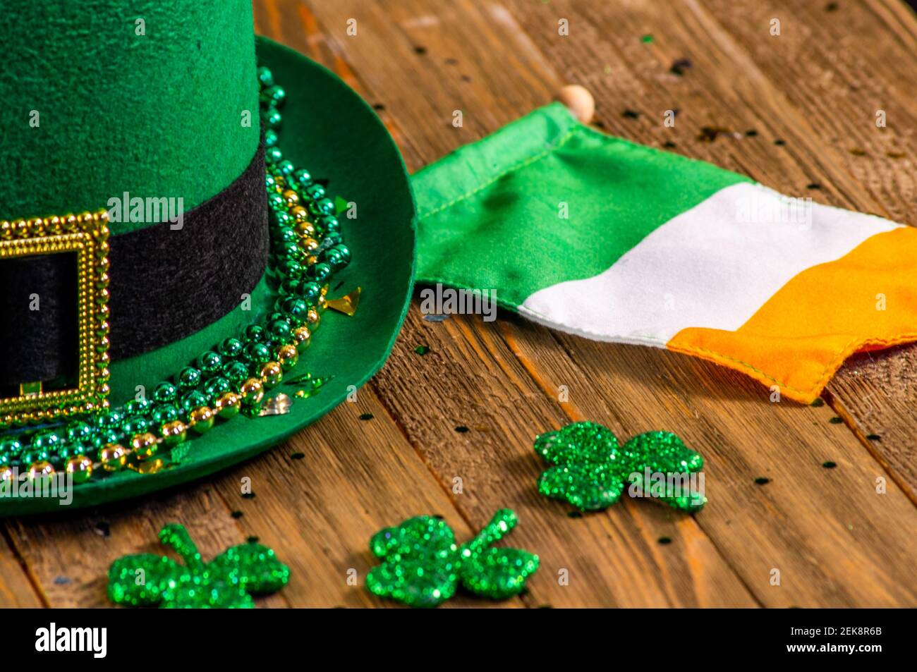 Saint Louis, Missouri - 21 febbraio 2021; cappello verde con fibbia seduta su un tavolo di legno accanto alla bandiera irlandese e gli sciamocchi che creano la mostra di San Patrizio Foto Stock