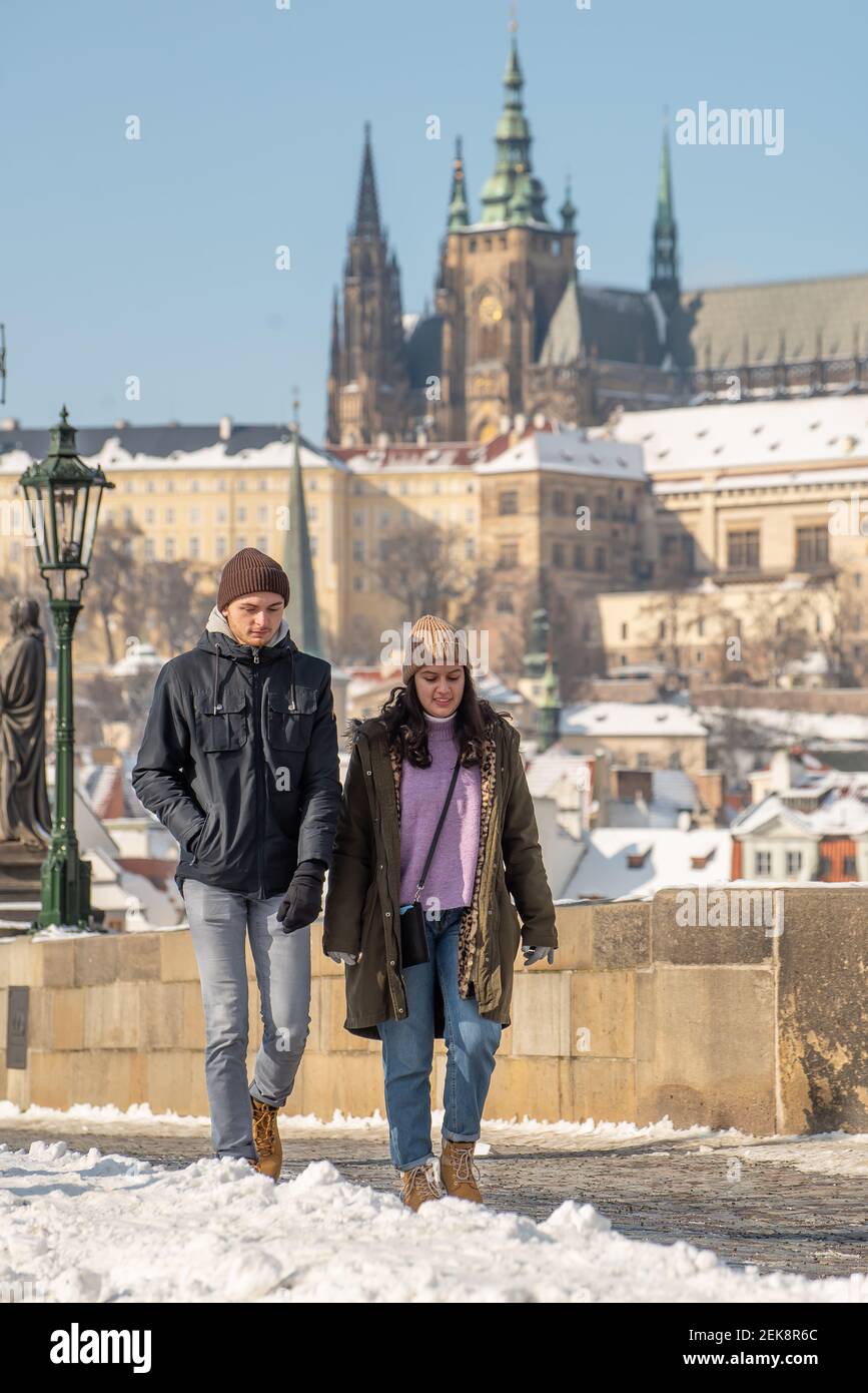 Praga, Repubblica Ceca. 02-23-2021. Giovane coppia nel centro di Praga a piedi e parlando sul Ponte Carlo, godendo di una giornata fredda durante il wi Foto Stock