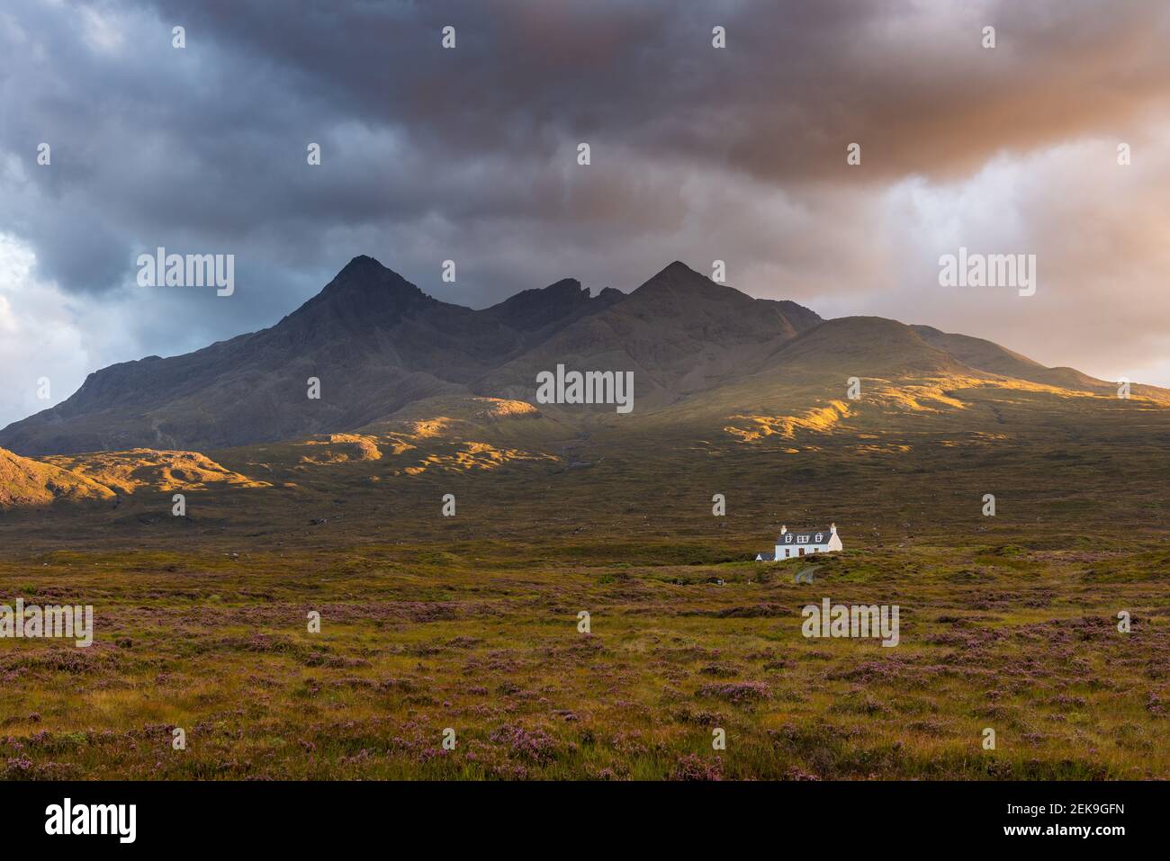 Splendida luce dorata con spettacolari nuvole scure sulla catena montuosa di Cuillin sull'Isola di Skye, Scozia, Regno Unito. Foto Stock