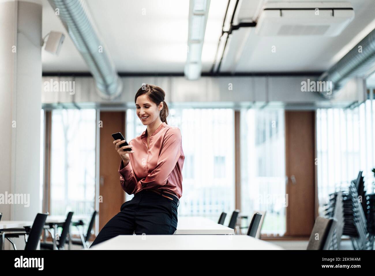 Imprenditore femminile che utilizza il telefono cellulare al tavolo da conferenza a bordo camera Foto Stock