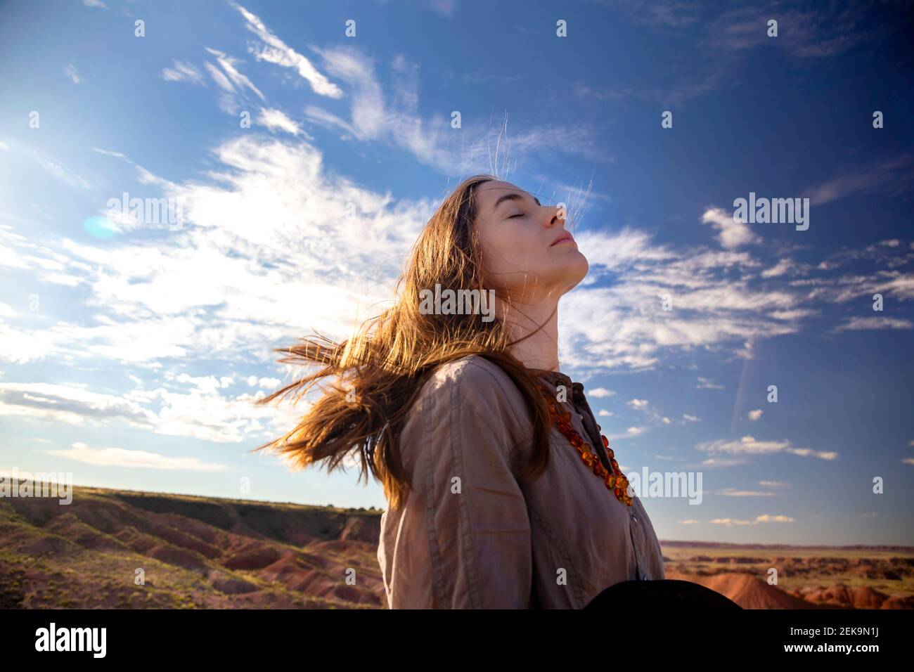 Donna turistica con gli occhi chiusi in piedi contro il cielo a Petrified Forest, parco nazionale, Arizona, Stati Uniti Foto Stock