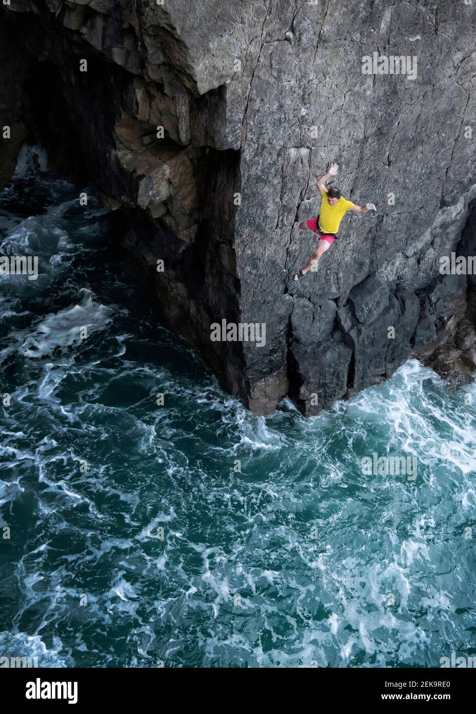 Scalatore di roccia maschile che salta in mare dalla scogliera Foto Stock