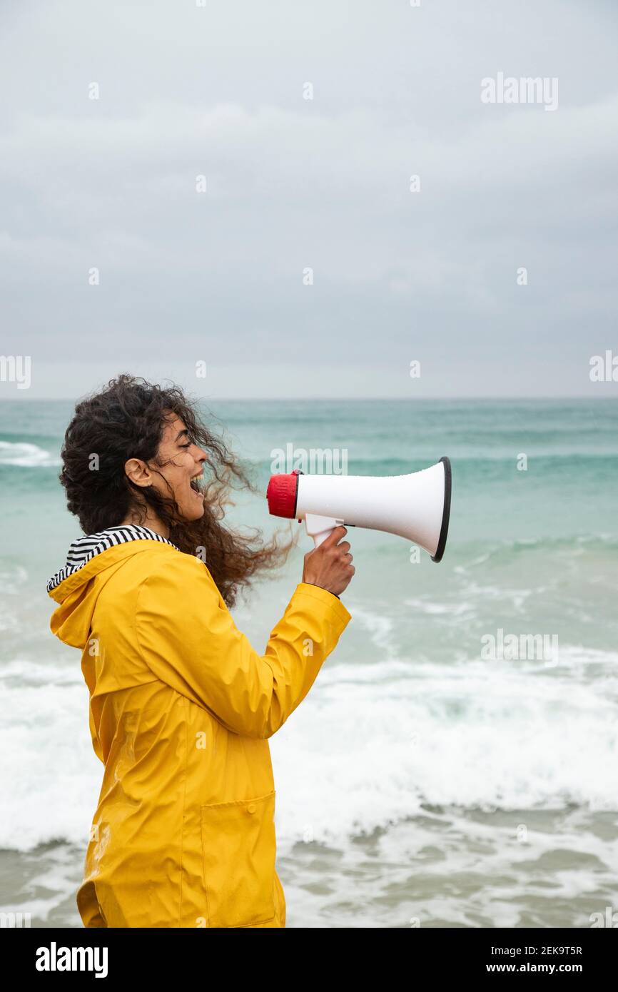 Donna che urla in megafono mentre si trova in spiaggia Foto Stock