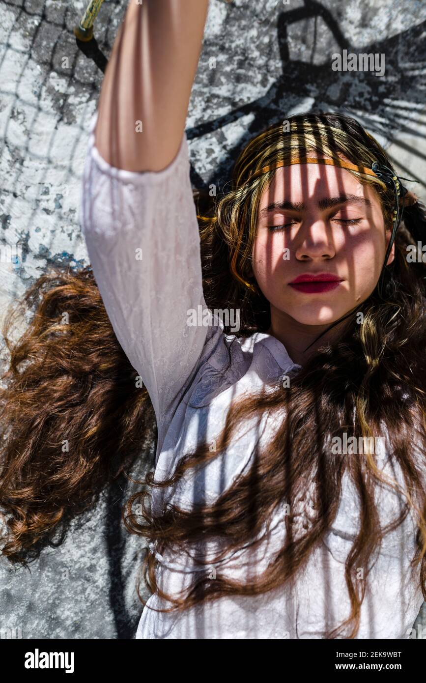 Bella donna nascondendo il viso con le mani mentre si trova su pavimento in cemento Foto Stock