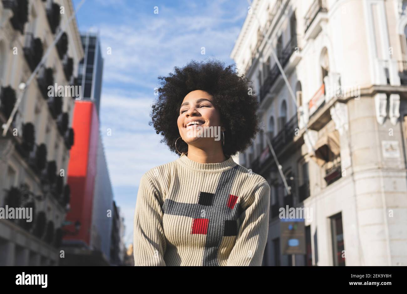 Giovane donna sorridente mentre si è in piedi in città Foto Stock