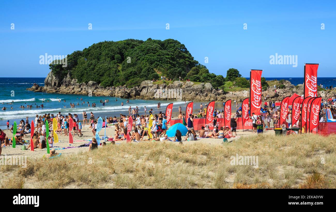 Folla sulla spiaggia di Mount Maunganui, Nuova Zelanda, in estate. Molti pennants di Coca-Cola sono stati lasciati dopo un festival estivo sponsorizzato Foto Stock