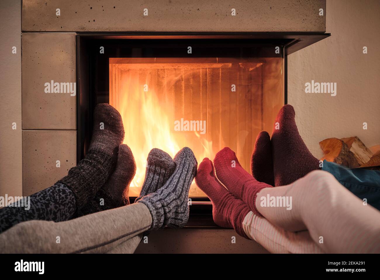 Famiglia che riscalda piedi in calze di lana da camino in soggiorno Foto Stock