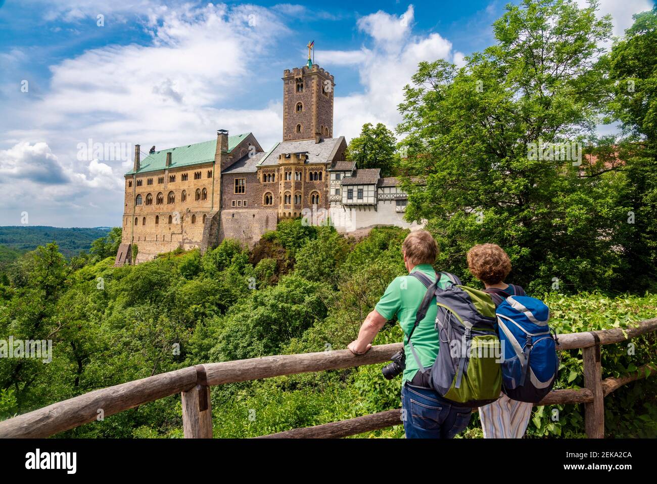 I turisti che guardano il Castello di Wartburg mentre si levano in piedi da una ringhiera in legno a Eisenach, Germania Foto Stock