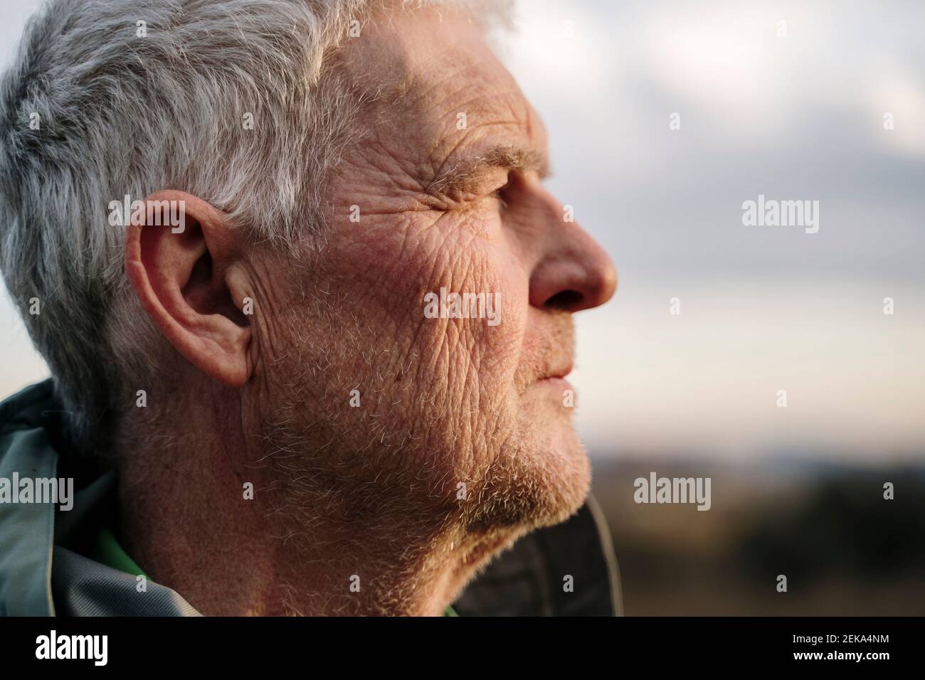 Uomo anziano con faccia rugosa contro durante il tramonto Foto Stock