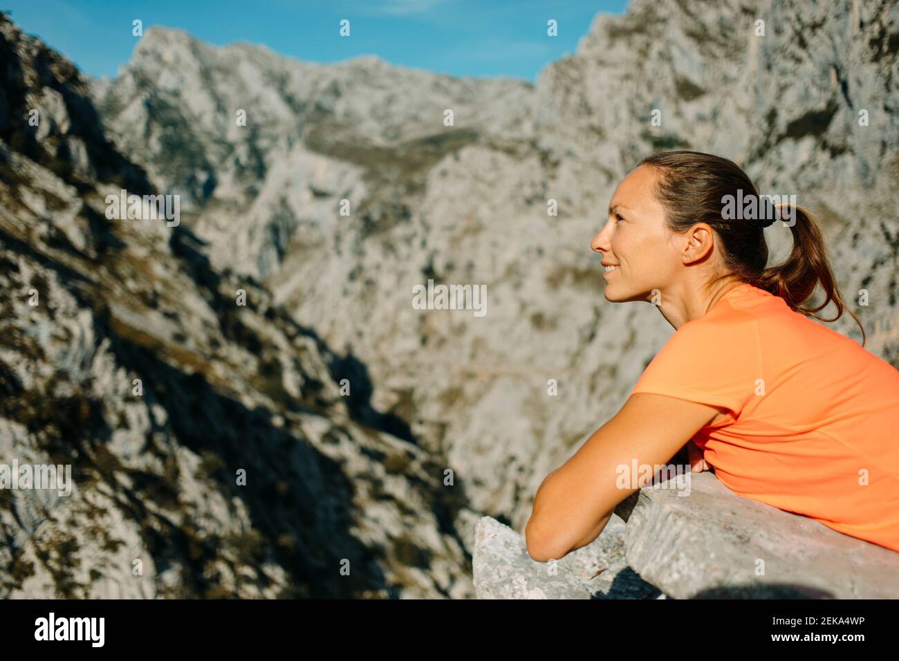 esploratore sorridente che guarda via mentre si sdraia sulla roccia a Cares Trail nel Parco Nazionale di Picos De Europe, Asturias, Spagna Foto Stock