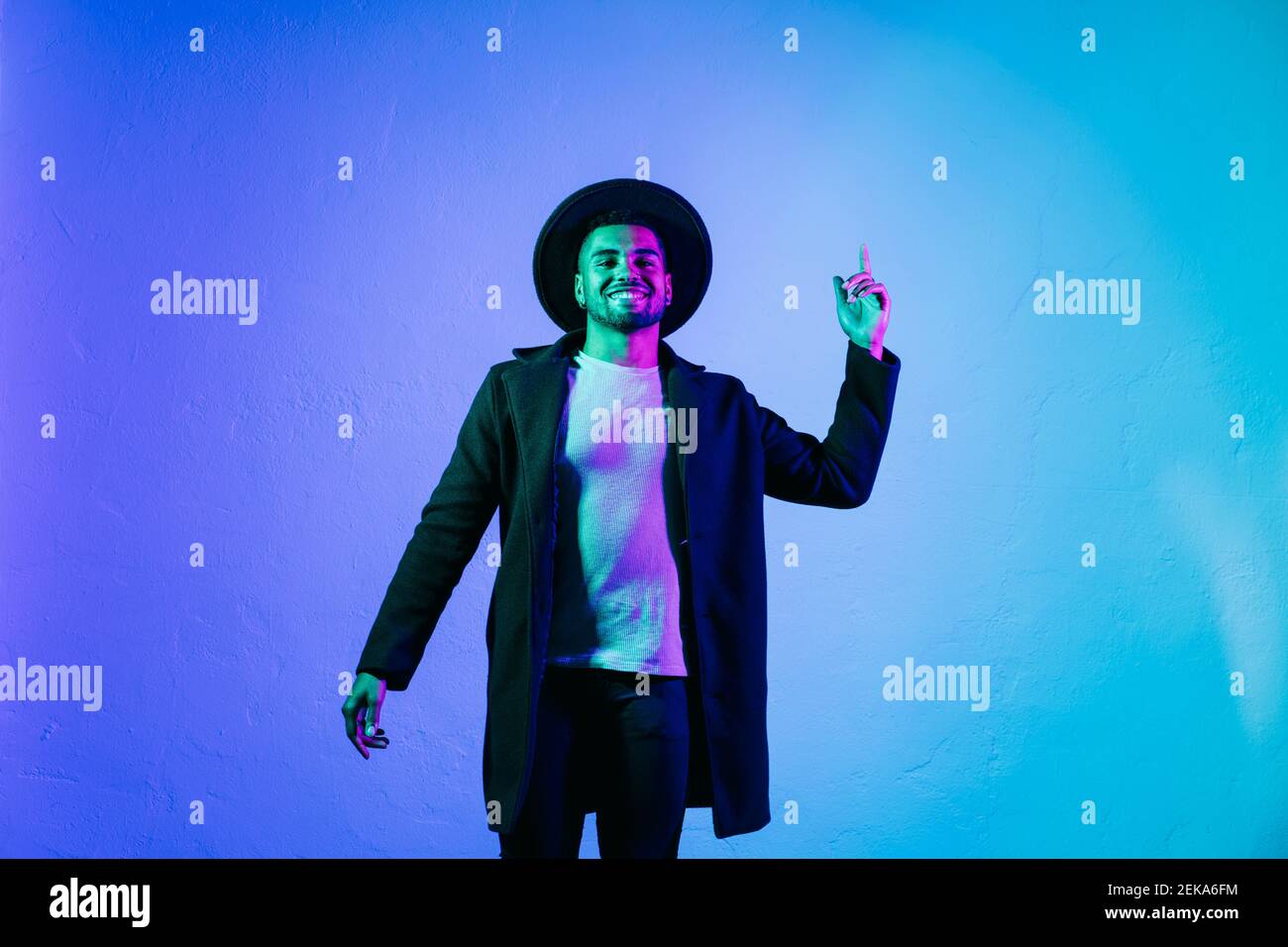 Uomo in abbigliamento casual gesturing mentre si levano in piedi su sfondo colorato Foto Stock