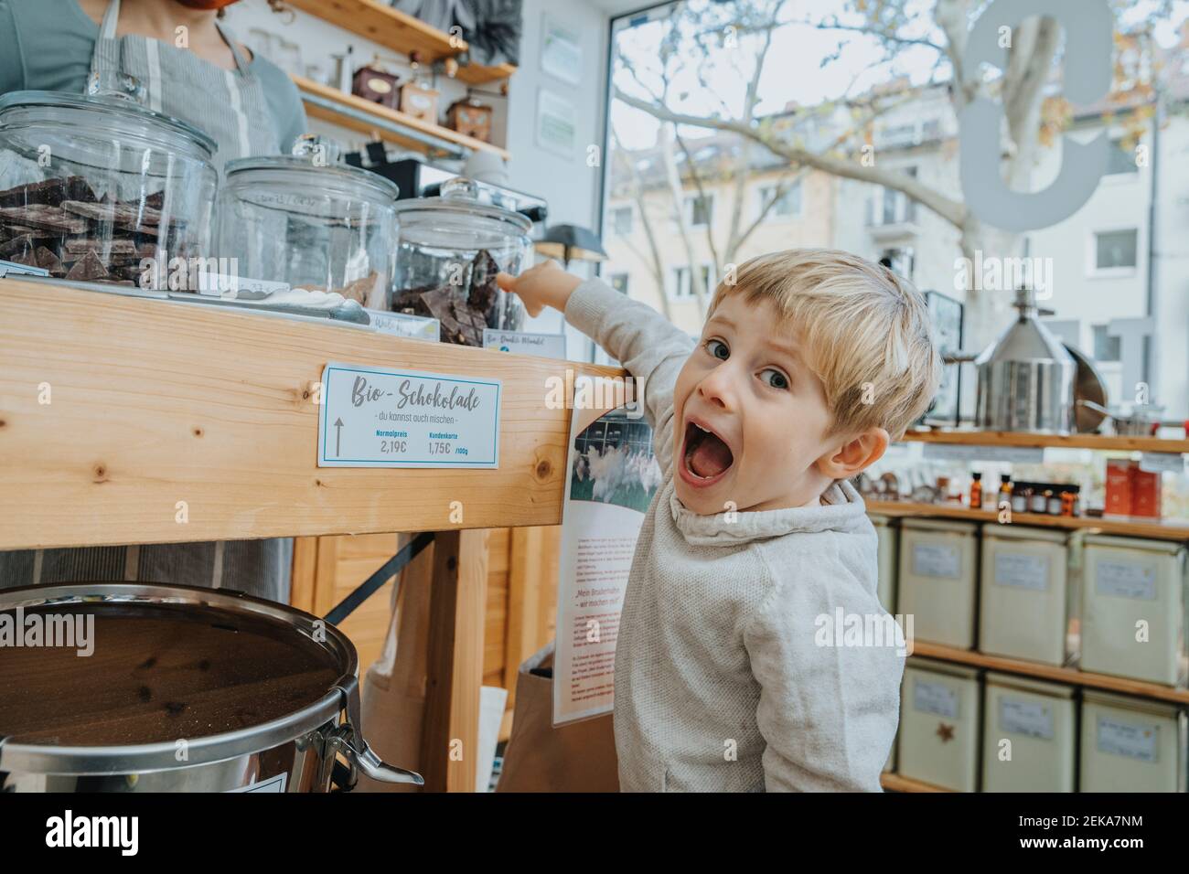 Ragazzo eccitato che indica il vaso di cioccolato nel negozio di caramelle Foto Stock