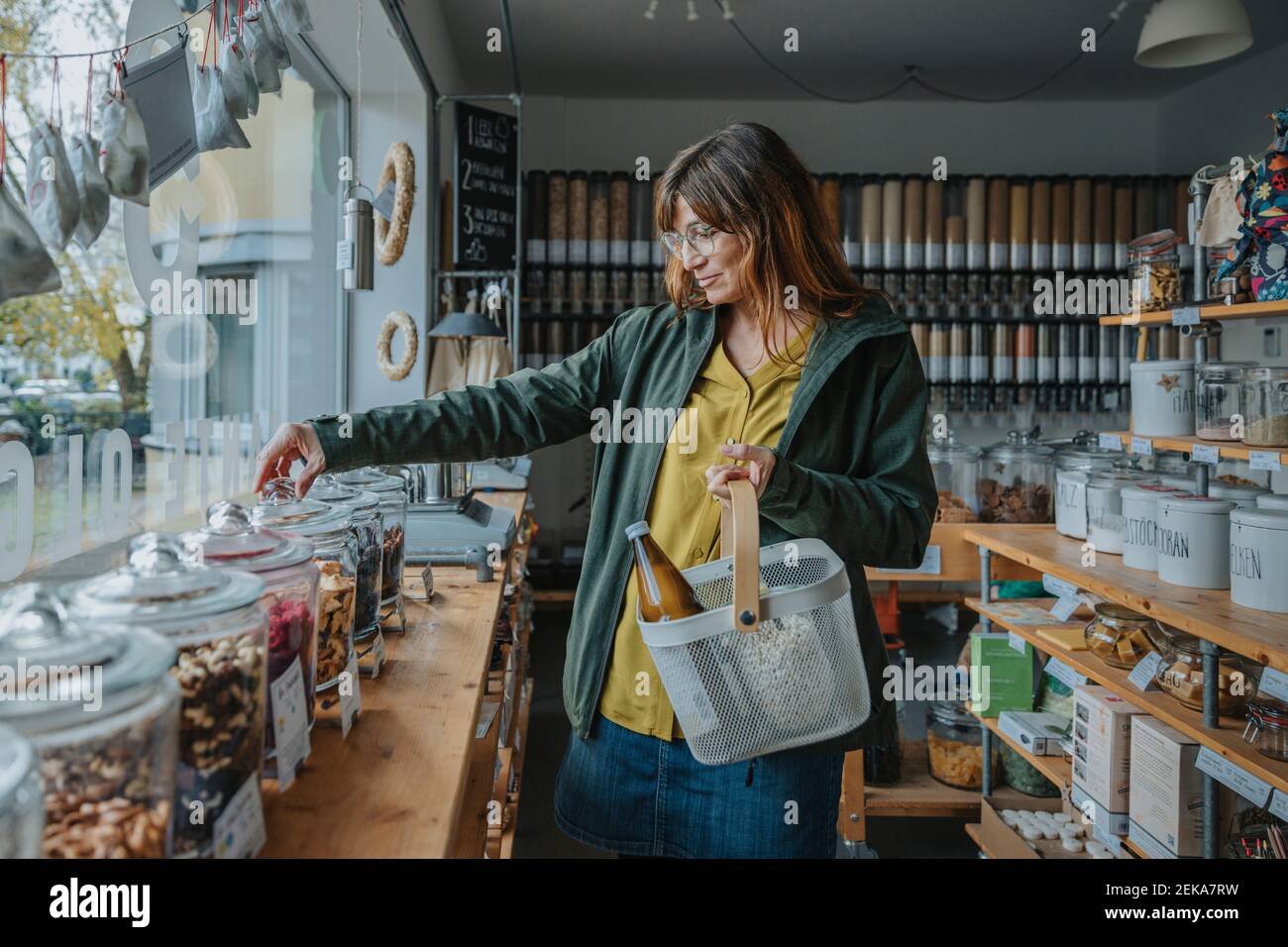 Donna che indossa occhiali con paniere shopping in negozio zero rifiuti Foto Stock