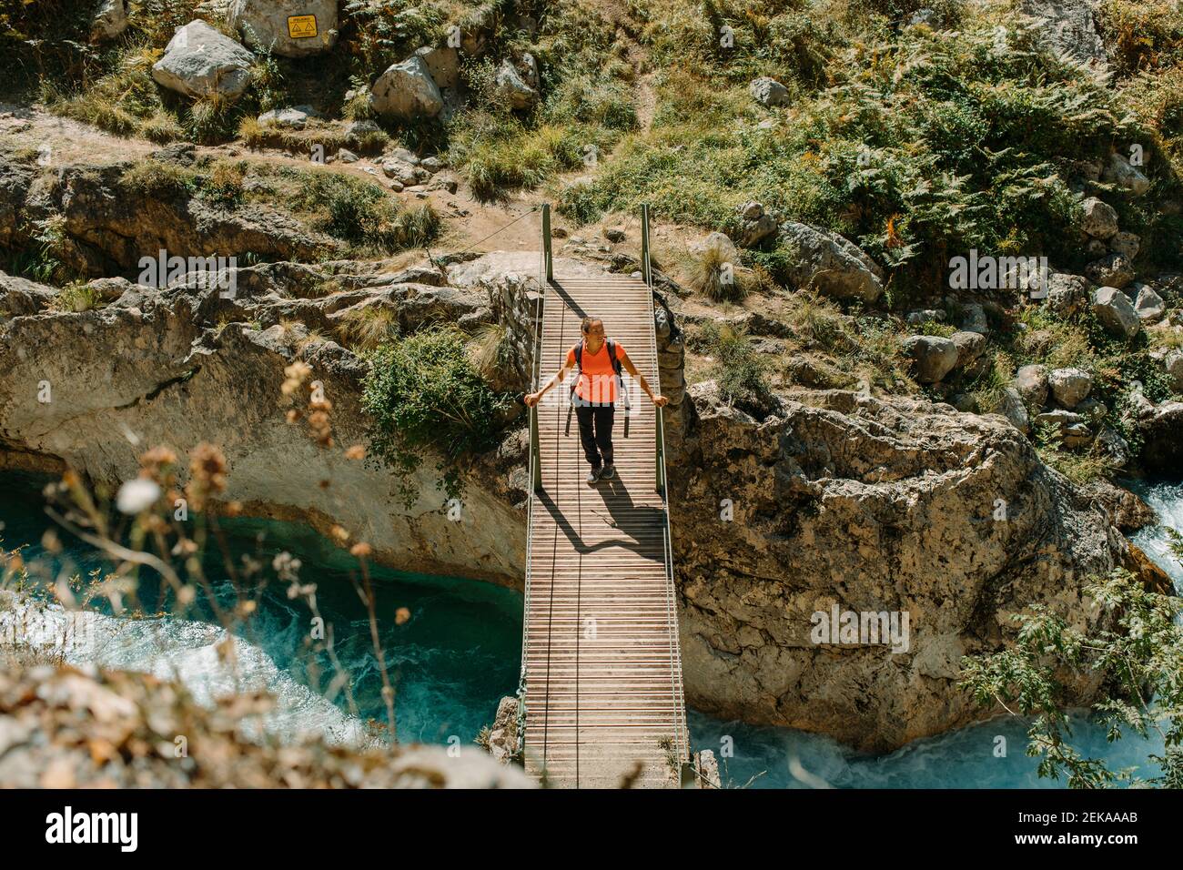 Donna che cammina sul ponte mentre esplorando Cares Trail nel Parco Nazionale Picos De Europe, Asturias, Spagna Foto Stock